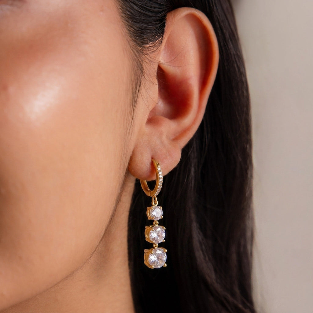 Gold-tone graduated stone hoop earring worn close-up
