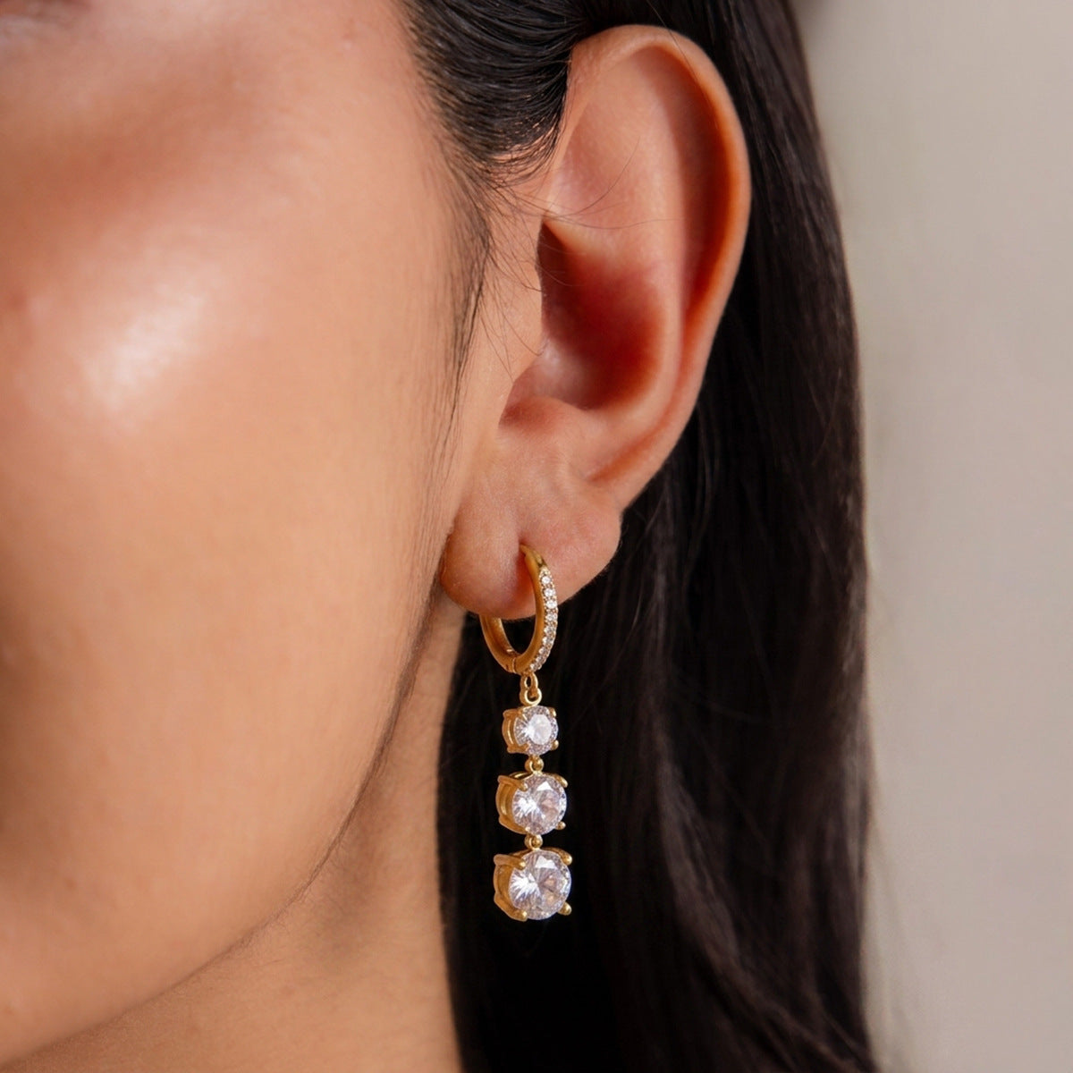 Gold-tone graduated stone hoop earring worn close-up