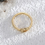 overhead view of slim gold plated band and interlaced knot