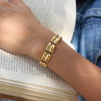 Polished link bracelet worn while holding a book