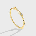 isolated gold plated twisted stacking ring with three clear stones