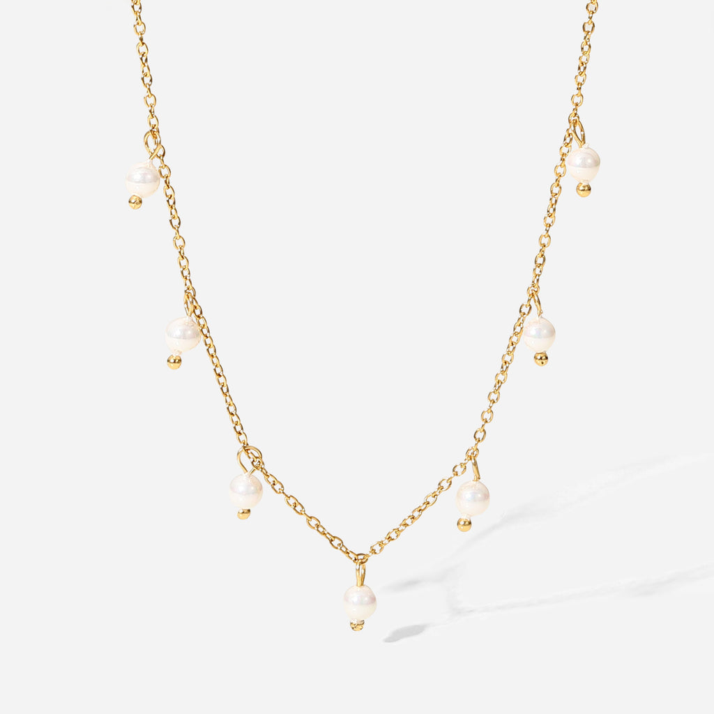 isolated gold plated necklace with unevenly spaced white bead drops