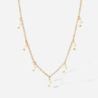 isolated gold plated necklace with unevenly spaced white bead drops