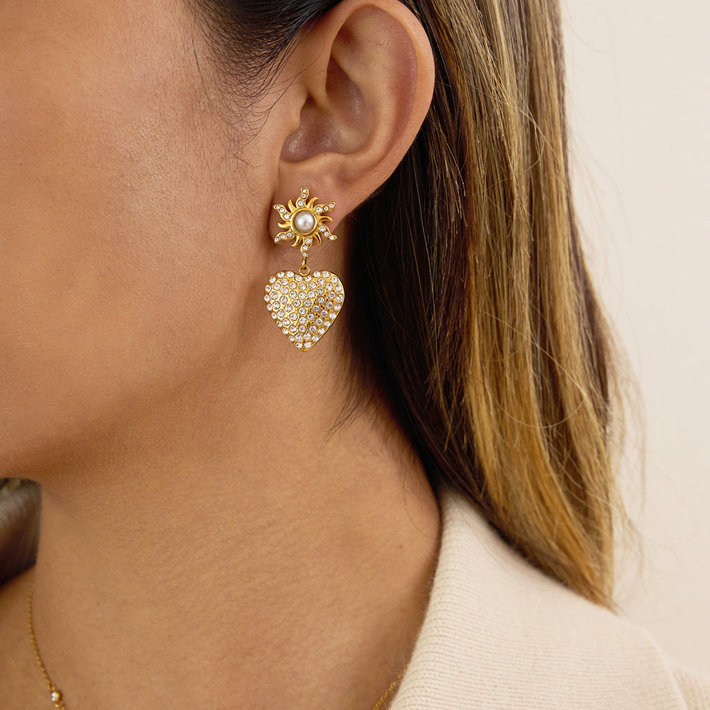 Model wearing gold-tone clear stone heart drop earrings