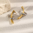 Two tone crossing curve earrings on a pale surface