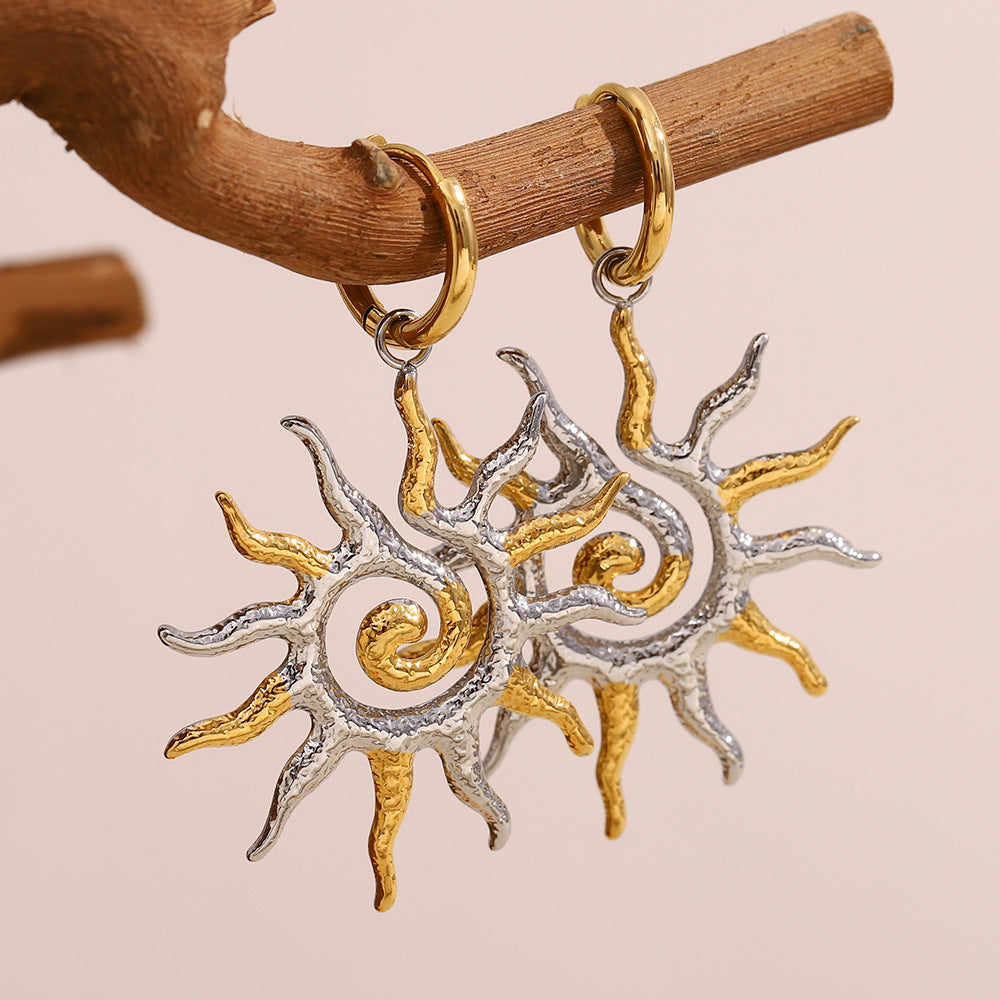 pair of two-tone spiral sun pendant earrings on natural wood