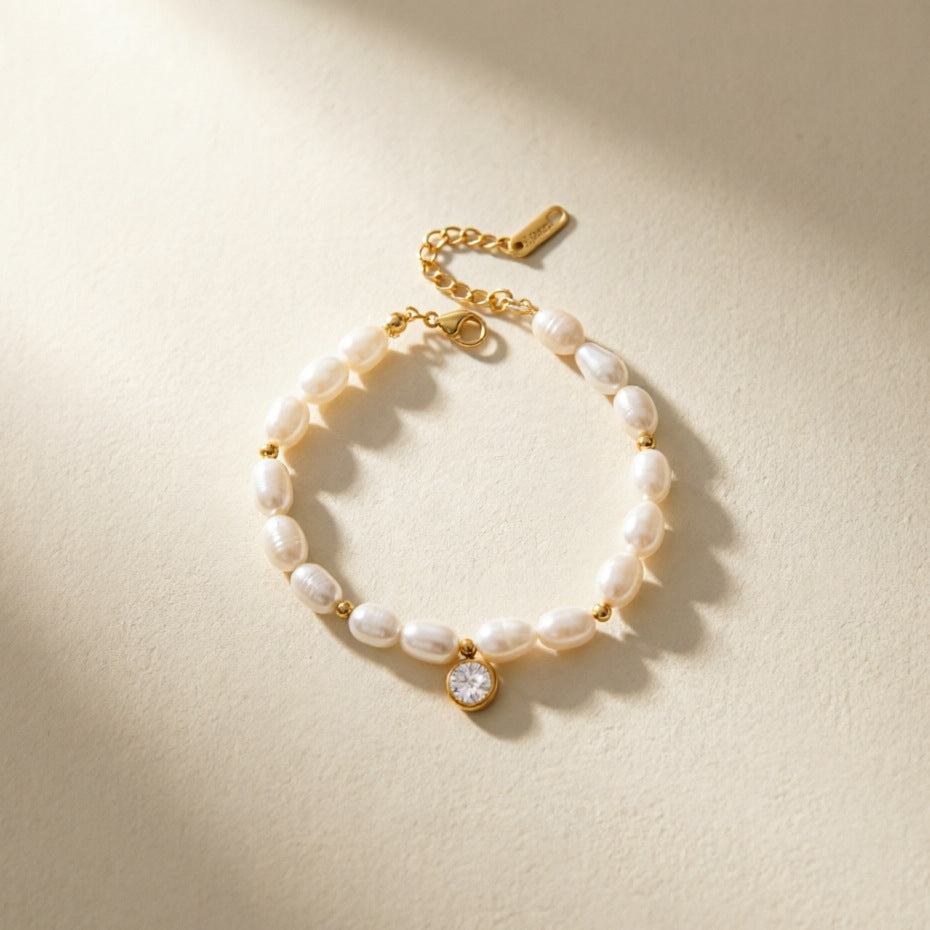 Gold plated bracelet with pearl-look beads on a neutral surface