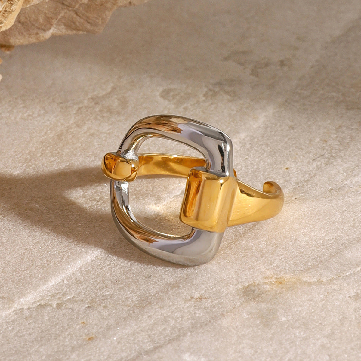 Rounded-square two-tone ring displayed on stone