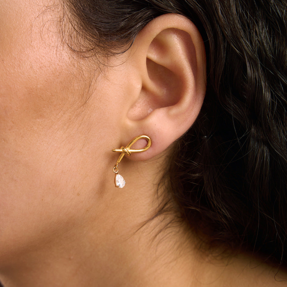 Knotted loop earring with clear pear drop worn close-up