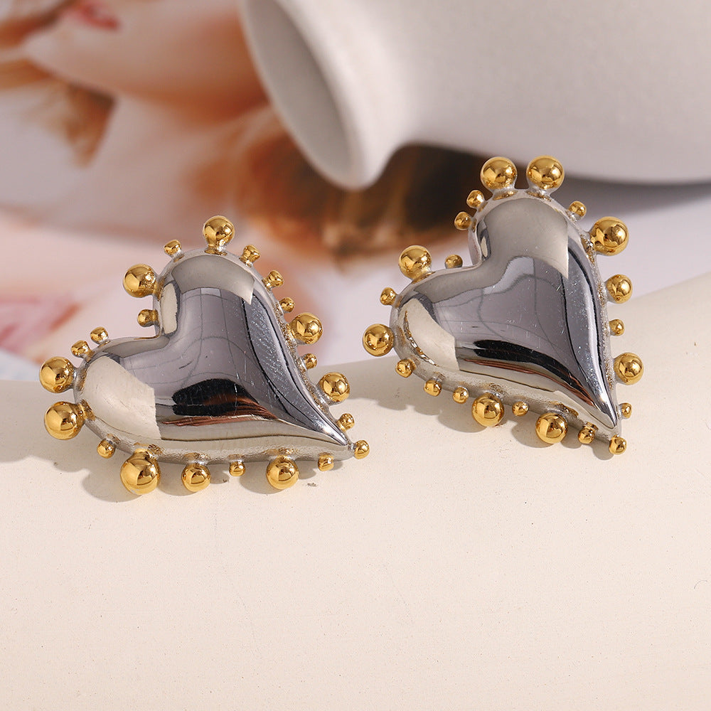 pair of polished two-tone heart stud earrings on a white display