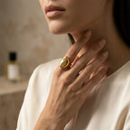 Gold-tone sculptural ring worn on a finger