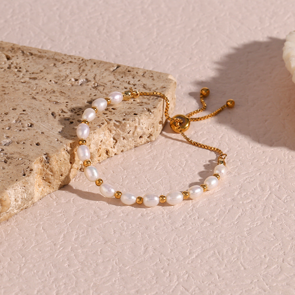 gold plated pearl slider bracelet arranged on a pale stone surface