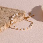 gold plated pearl slider bracelet arranged on a pale stone surface