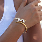 Three-stone gold-tone cuff shown on the wrist