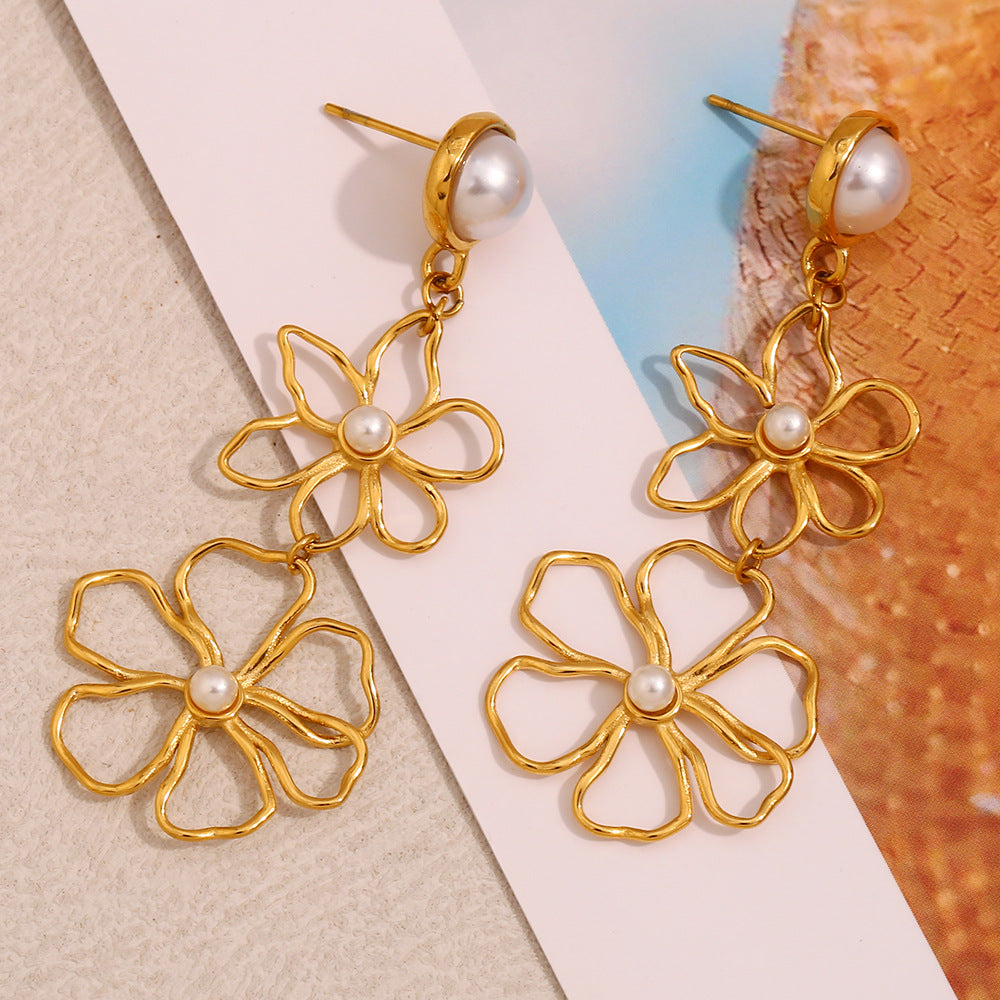 gold plated open-line flower drop earrings styled on a neutral surface