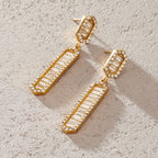 Pair of halo-bordered bar earrings on a pale surface