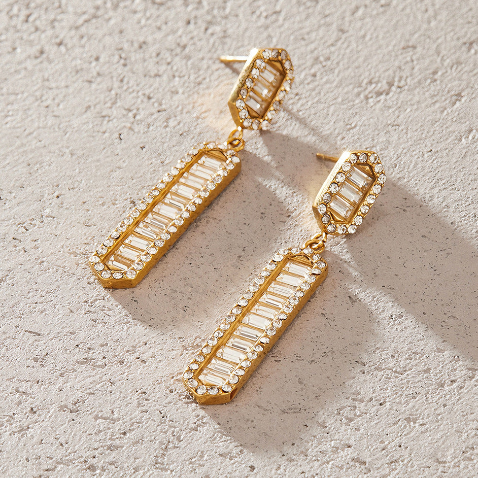 Pair of halo-bordered bar earrings on a pale surface