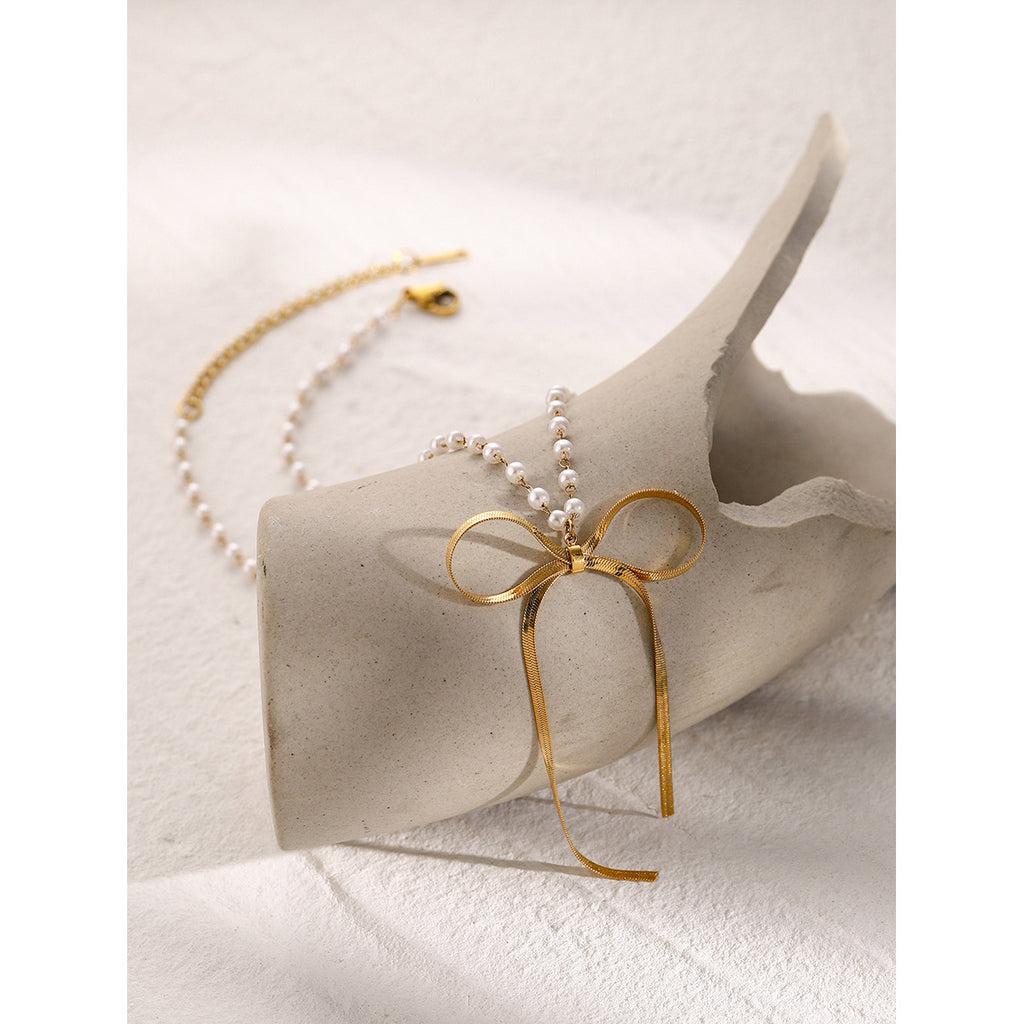 Bow and pearl-look bead necklace arranged on a display block