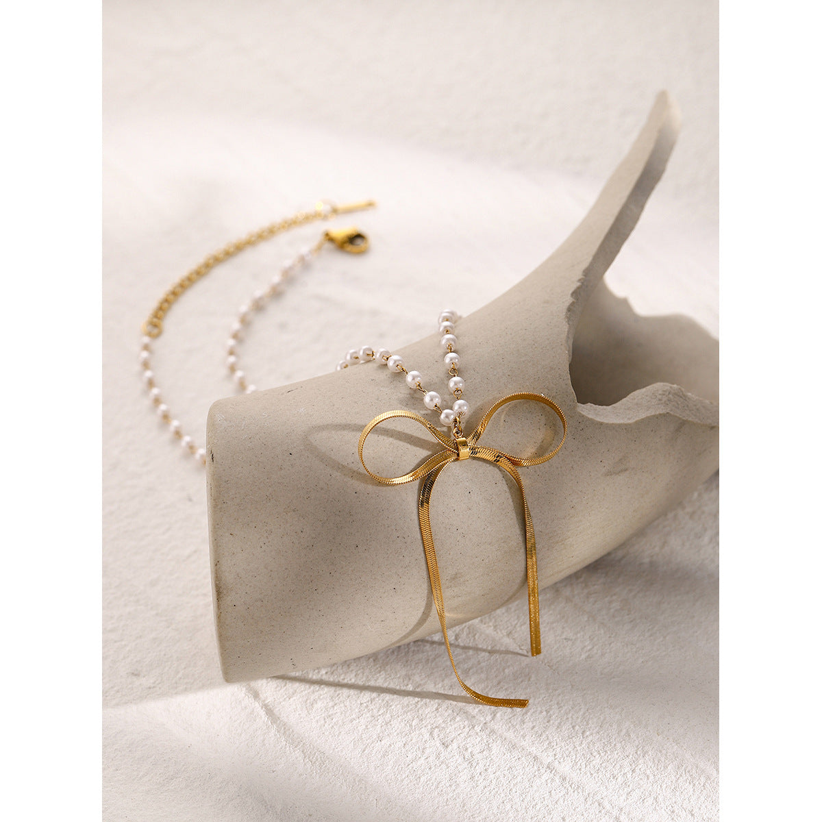 Bow and pearl-look bead necklace arranged on a display block