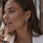 Green resin and silver tone C hoop worn on an ear