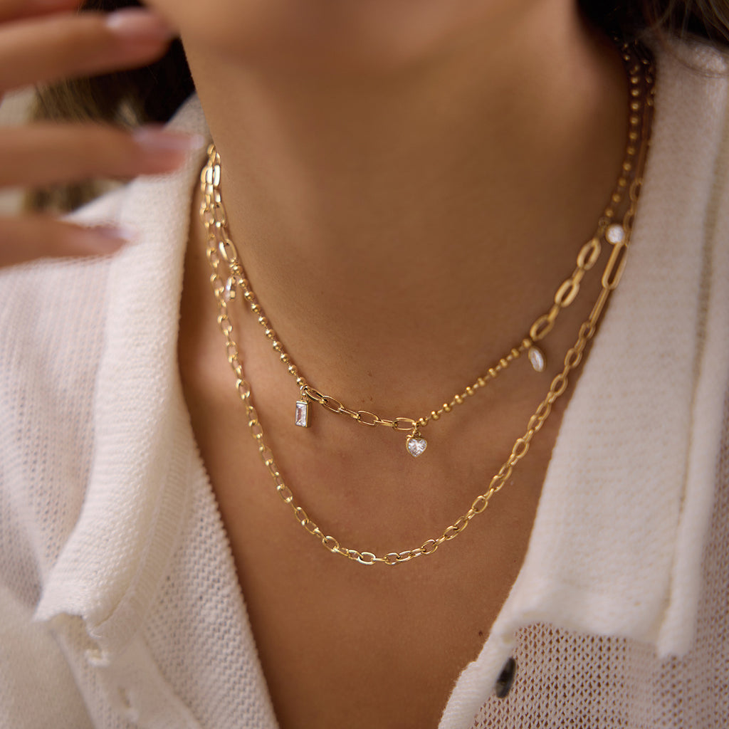 Mixed charm necklace layered with an elongated-link necklace