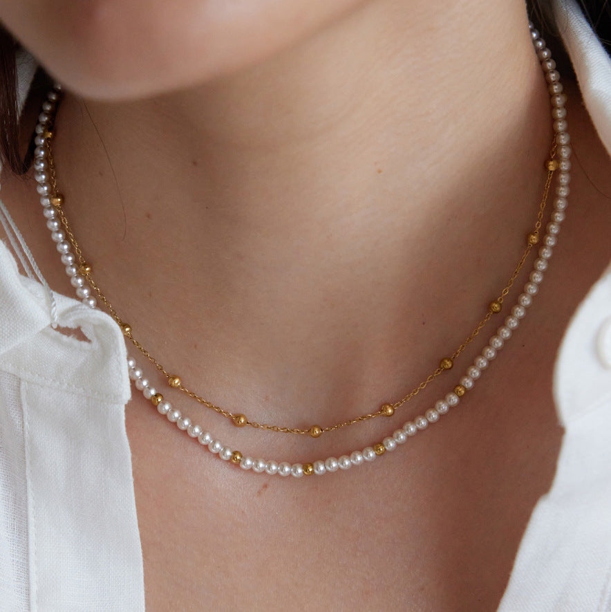 Layered acrylic pearl and small-bead chain necklace worn close-up