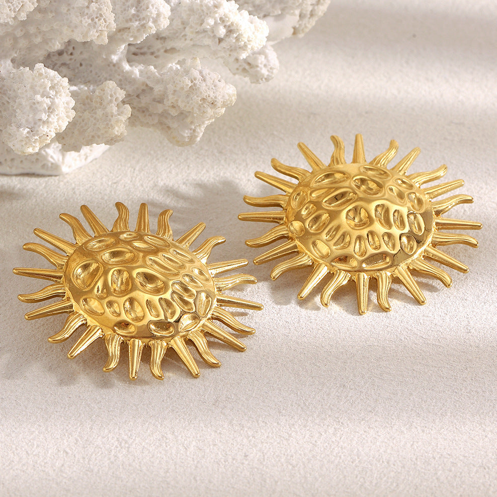 textured sunburst statement earrings styled beside white coral