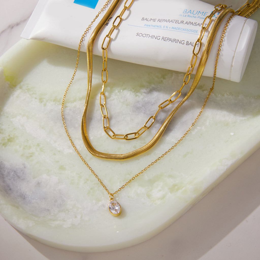 Layered gold tone necklace arranged on a tray