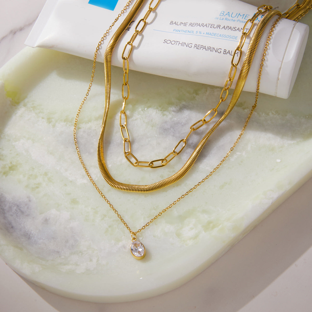 Layered gold tone necklace arranged on a tray