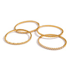 Four gold-tone stackable bangle designs shown together
