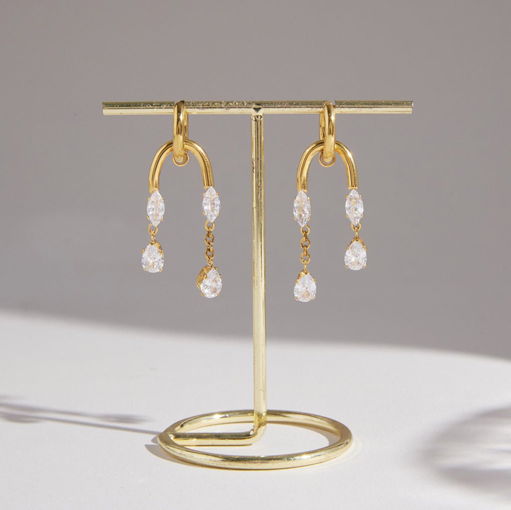 Pair of clear stone tassel earrings hanging on a stand