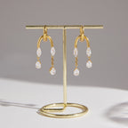 Pair of clear stone tassel earrings hanging on a stand