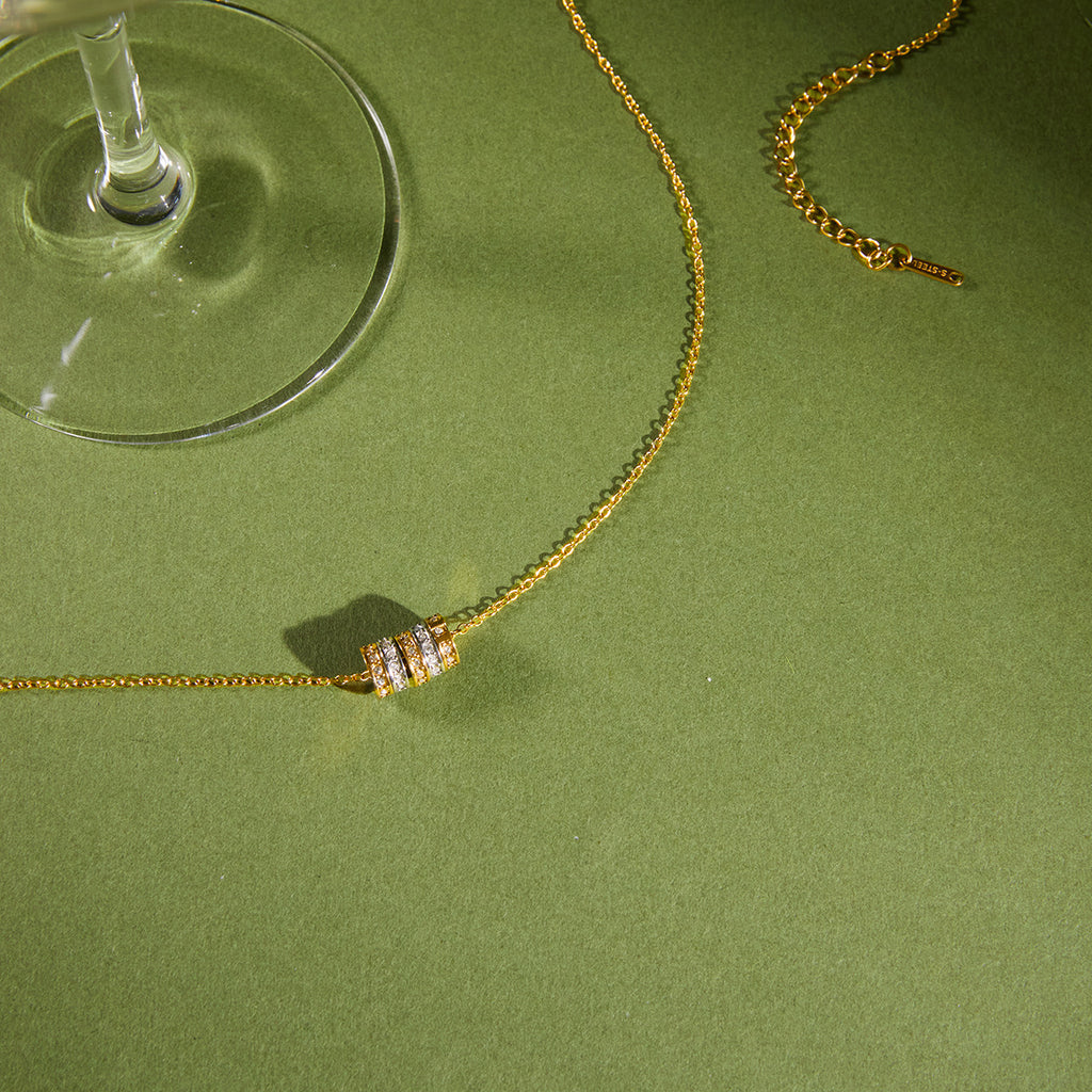 Multicolor cube station necklace arranged beside a glass
