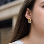 White marbled resin stud with gold tone cap worn on an ear