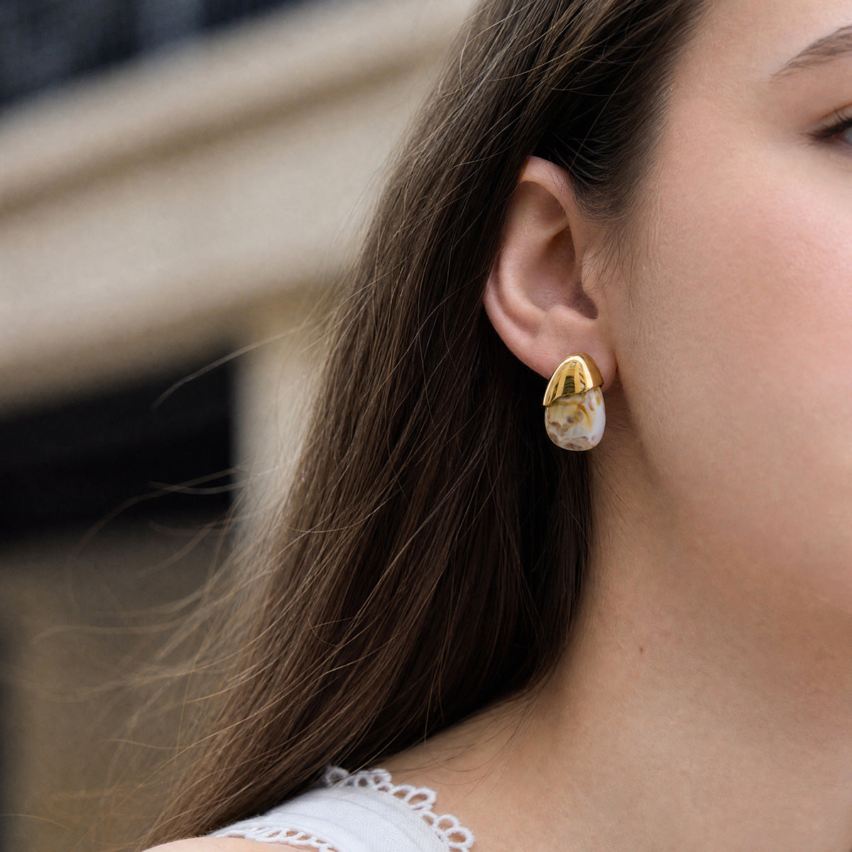White marbled resin stud with gold tone cap worn on an ear