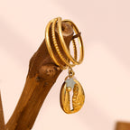 gold plated cowrie charm open ring displayed on a branch