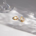 Twisted rhinestone hoops beside a glass