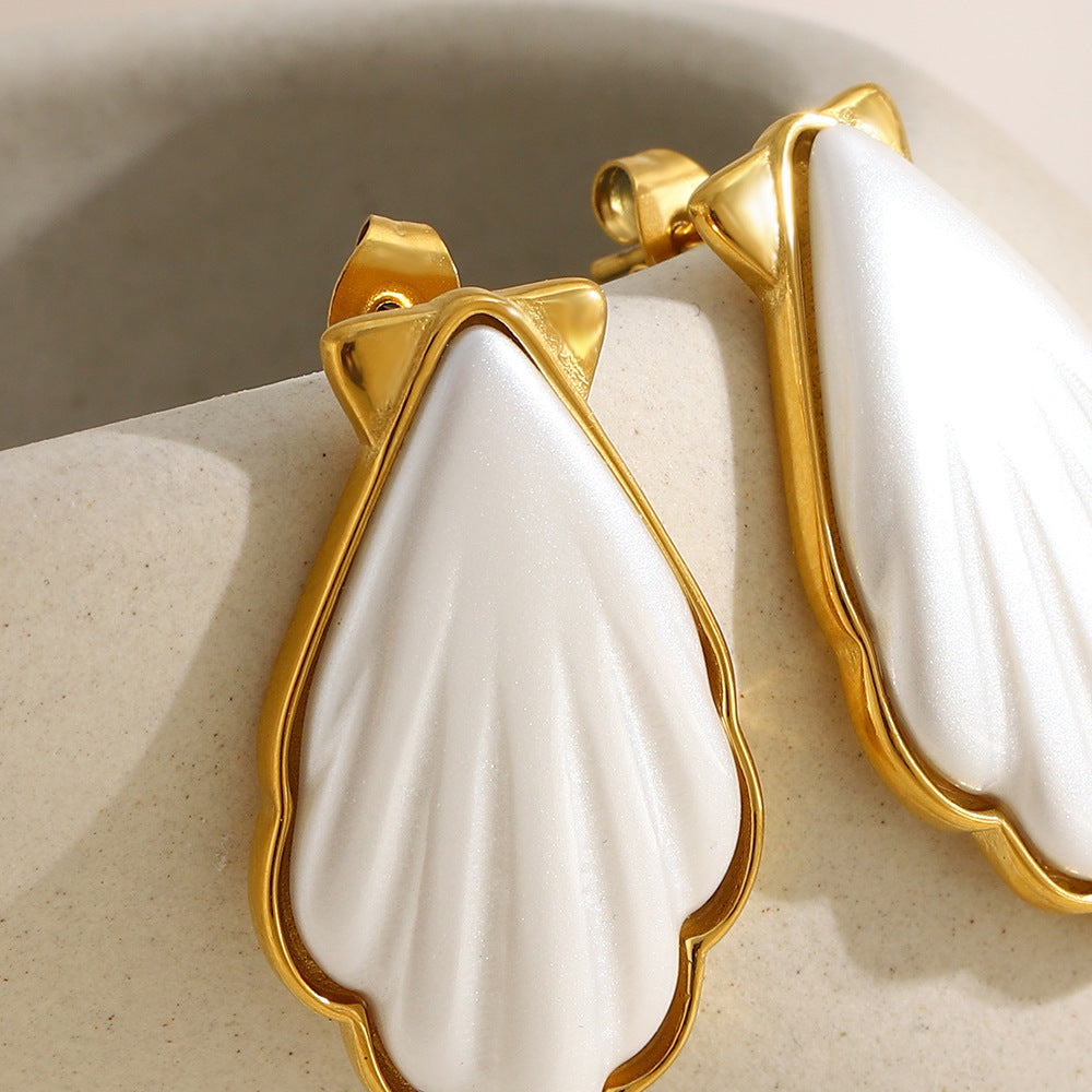 close-up of ribbed white acrylic shell earrings in gold plated frames