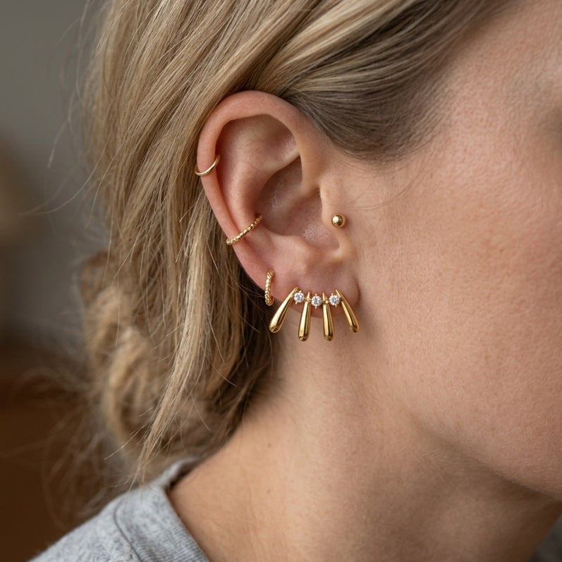 Gold-tone radiating drop stud worn on ear