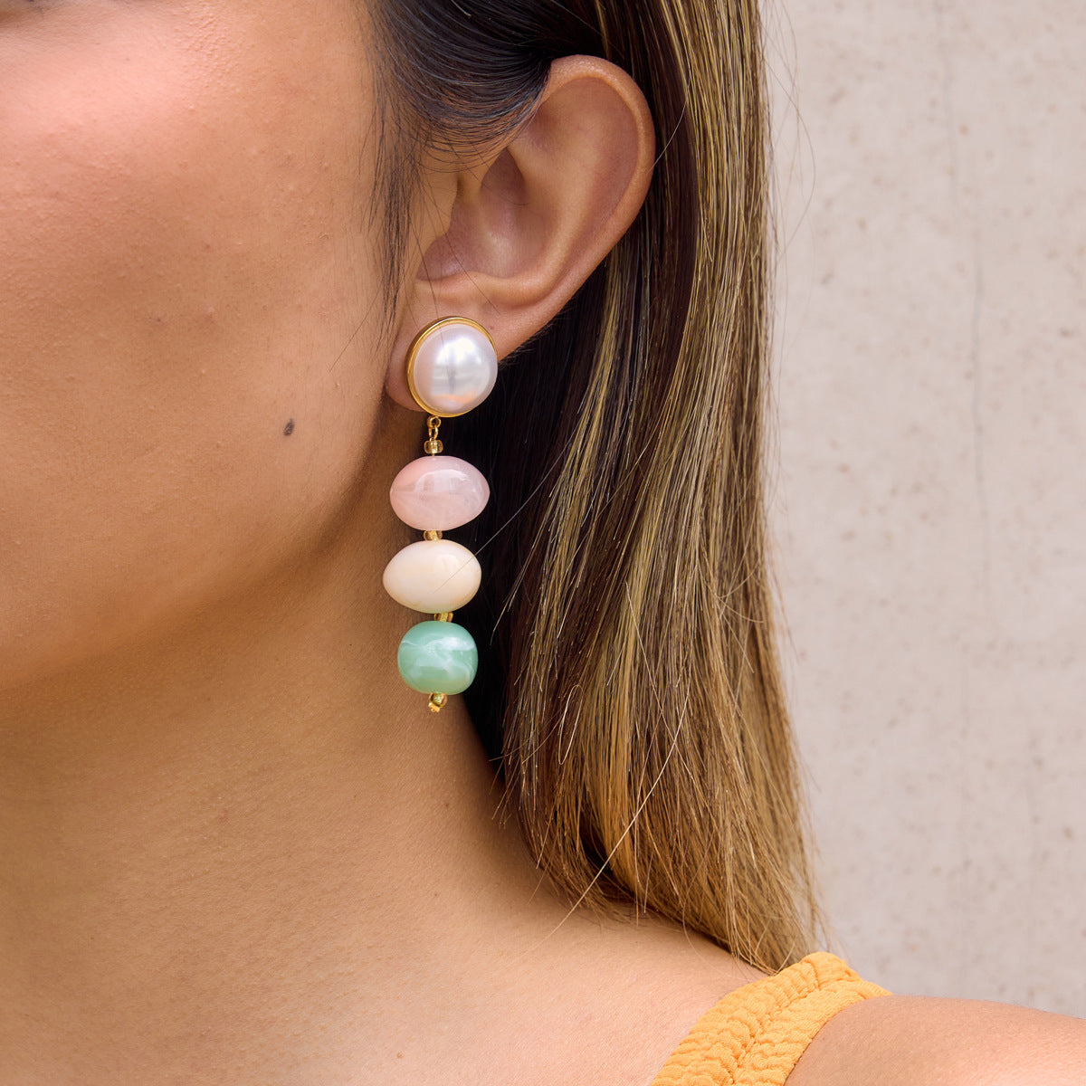 Pink cream and green drop earring worn on a lobe