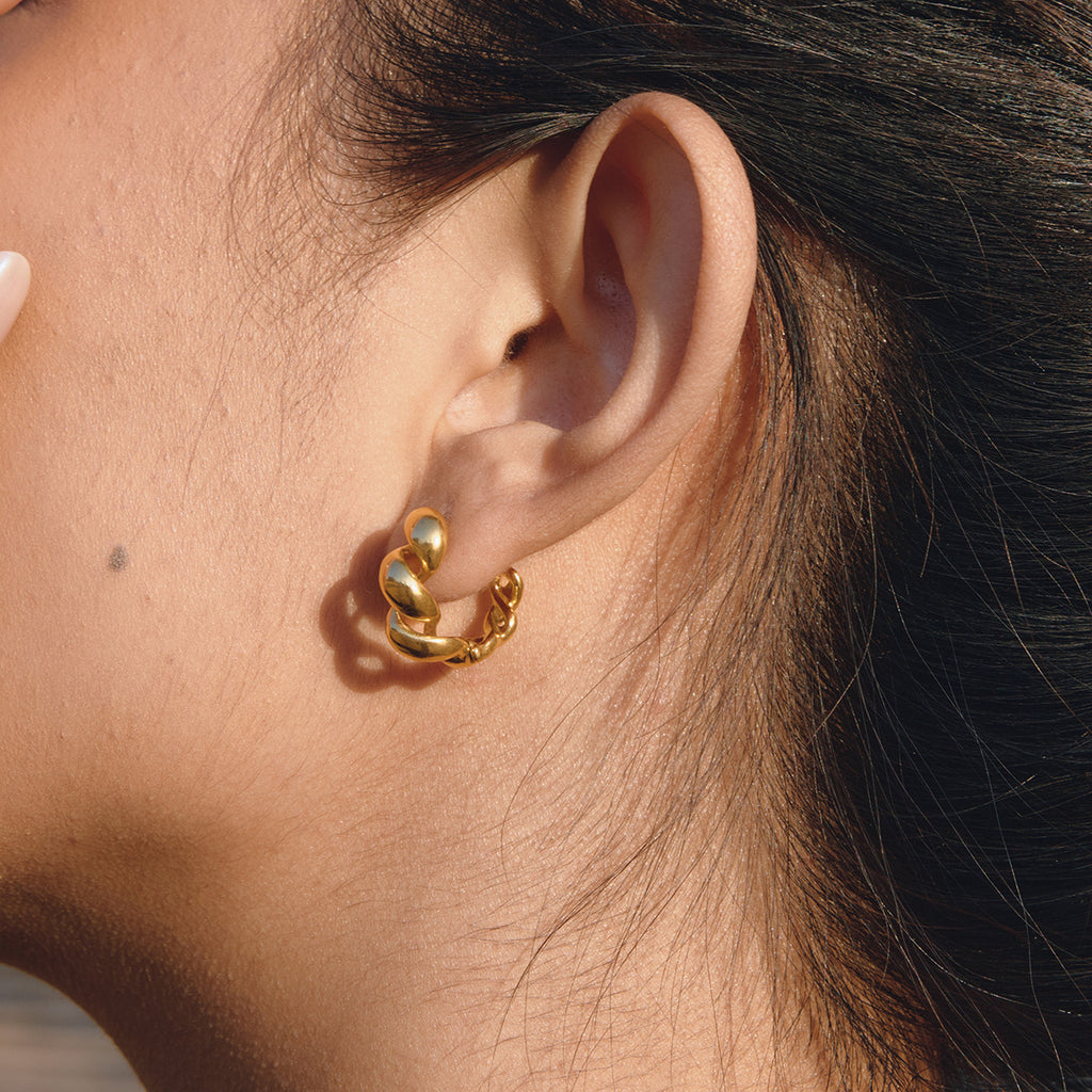 Gold tone sculptural hoop shown in profile