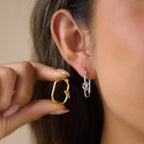 Silver tone knot hoop worn with gold tone version held nearby
