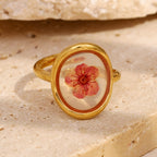gold plated dried flower ring styled against a pale stone display
