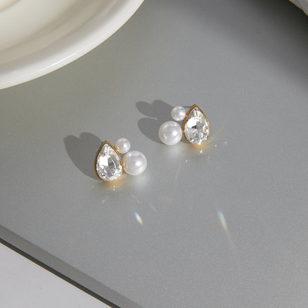 pair of gold plated pear-cut pearlized stud earrings on a tray