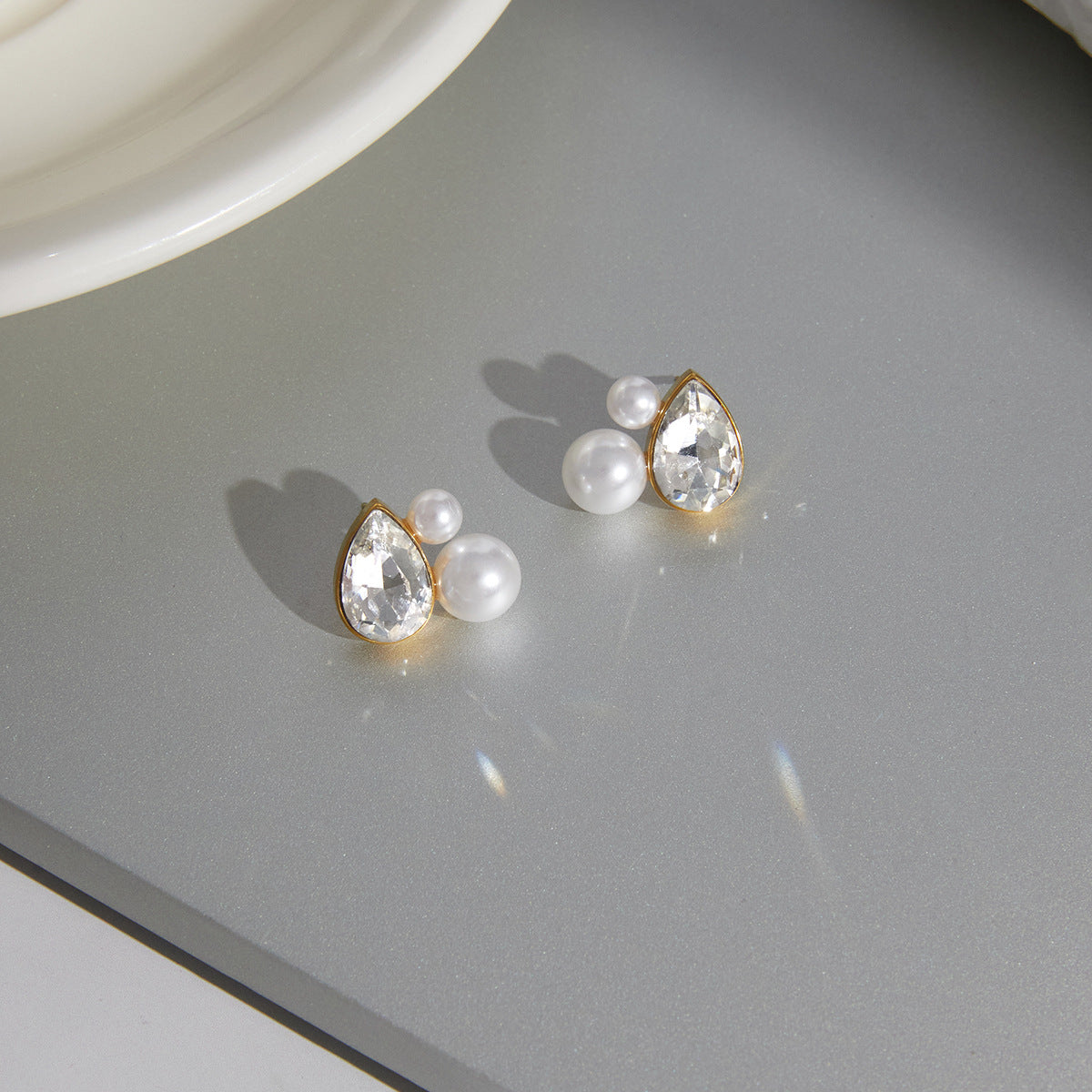 pair of gold plated pear-cut pearlized stud earrings on a tray