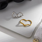 Two metallic versions of the wavy ring on a gray surface