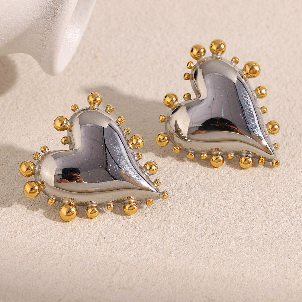 two-tone stainless steel beaded heart stud earrings on cream fabric