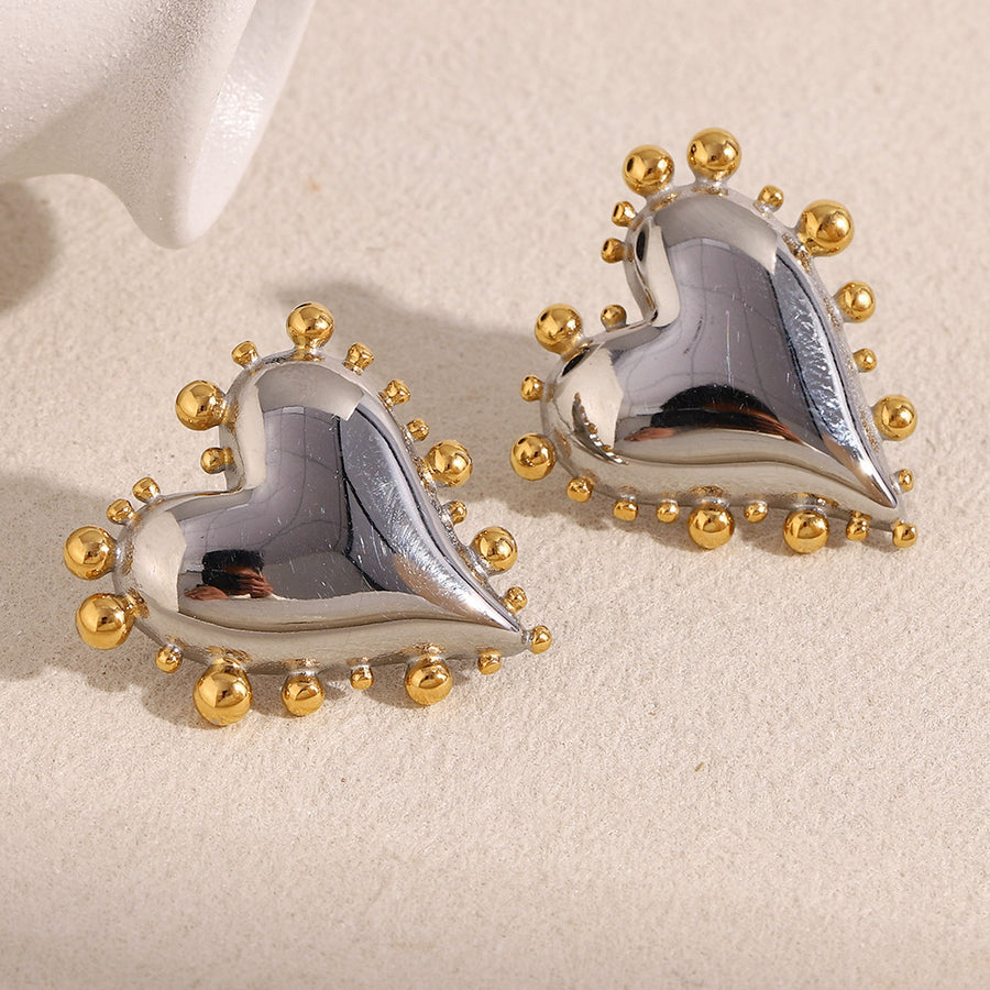 two-tone stainless steel beaded heart stud earrings on cream fabric