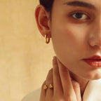 Smooth gold-tone hoop earring worn on an ear