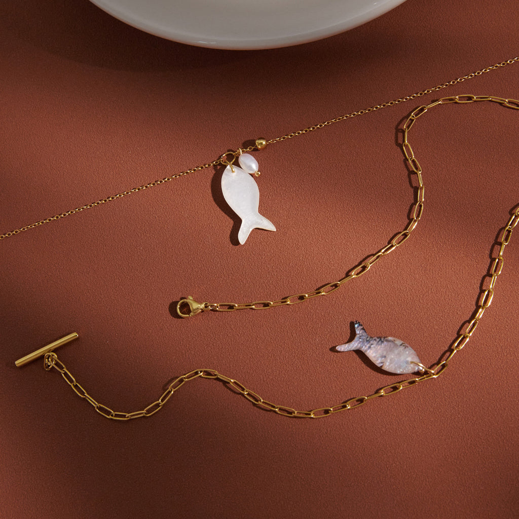 White and mottled gray fish pendant necklaces arranged together